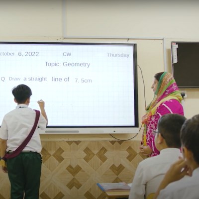 A student of Pakistan School Muscat engaging with a Geometry lesson on a SMART Board in front of his class and teacher